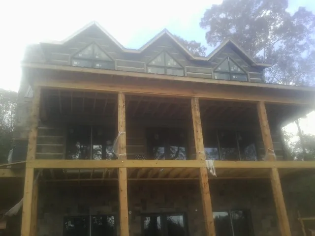 Dormers and porch framing on a large log home under construction — Roof Coating work by our crew in Lewis