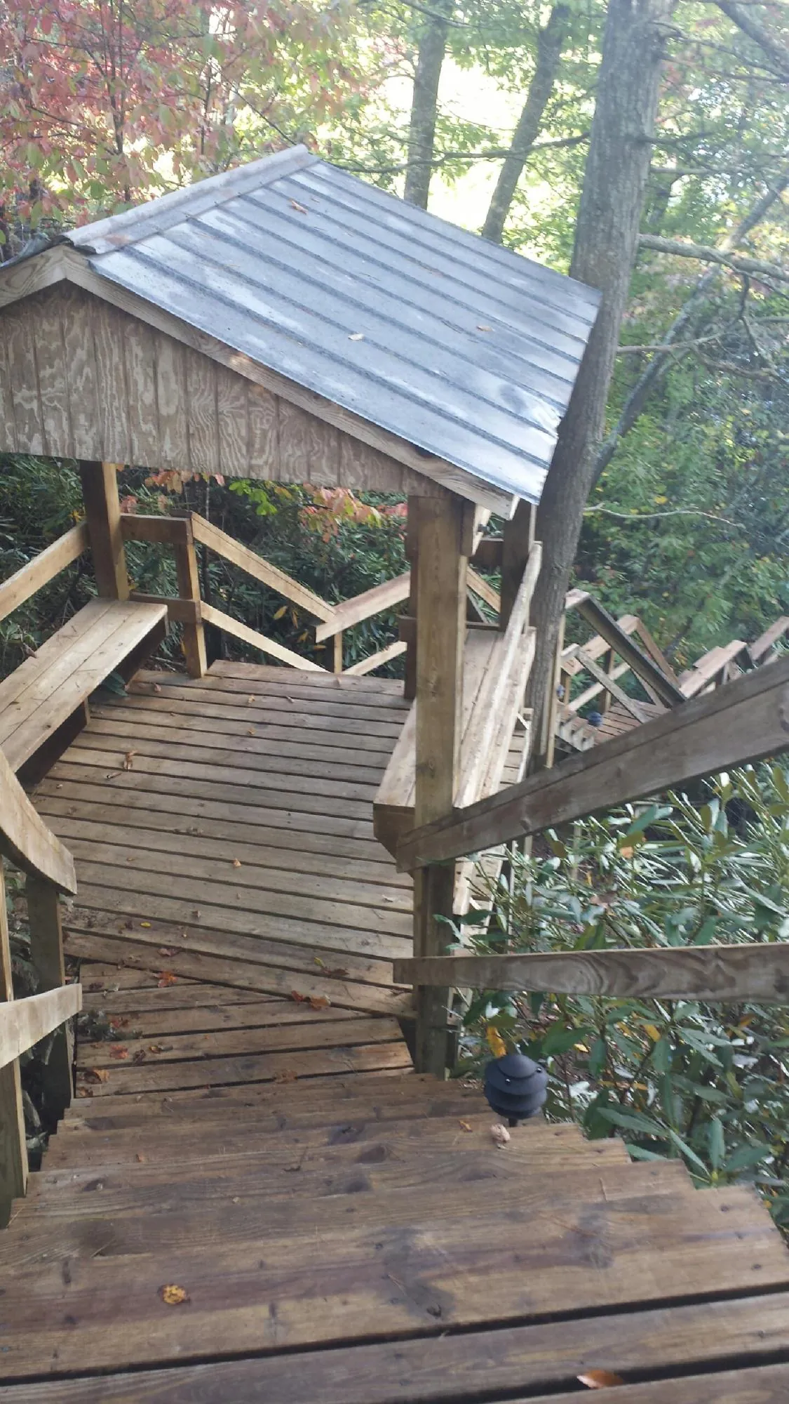 Metal roofed shelter over wooden steps on a wooded walkway — Skylight Repair & Installation work by our crew in Lewis